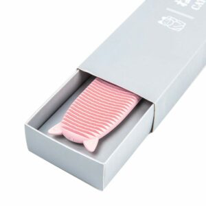 A pink cat styled cat comb inside a grey box